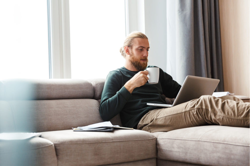 Man with ostomy sitting on couch on computer