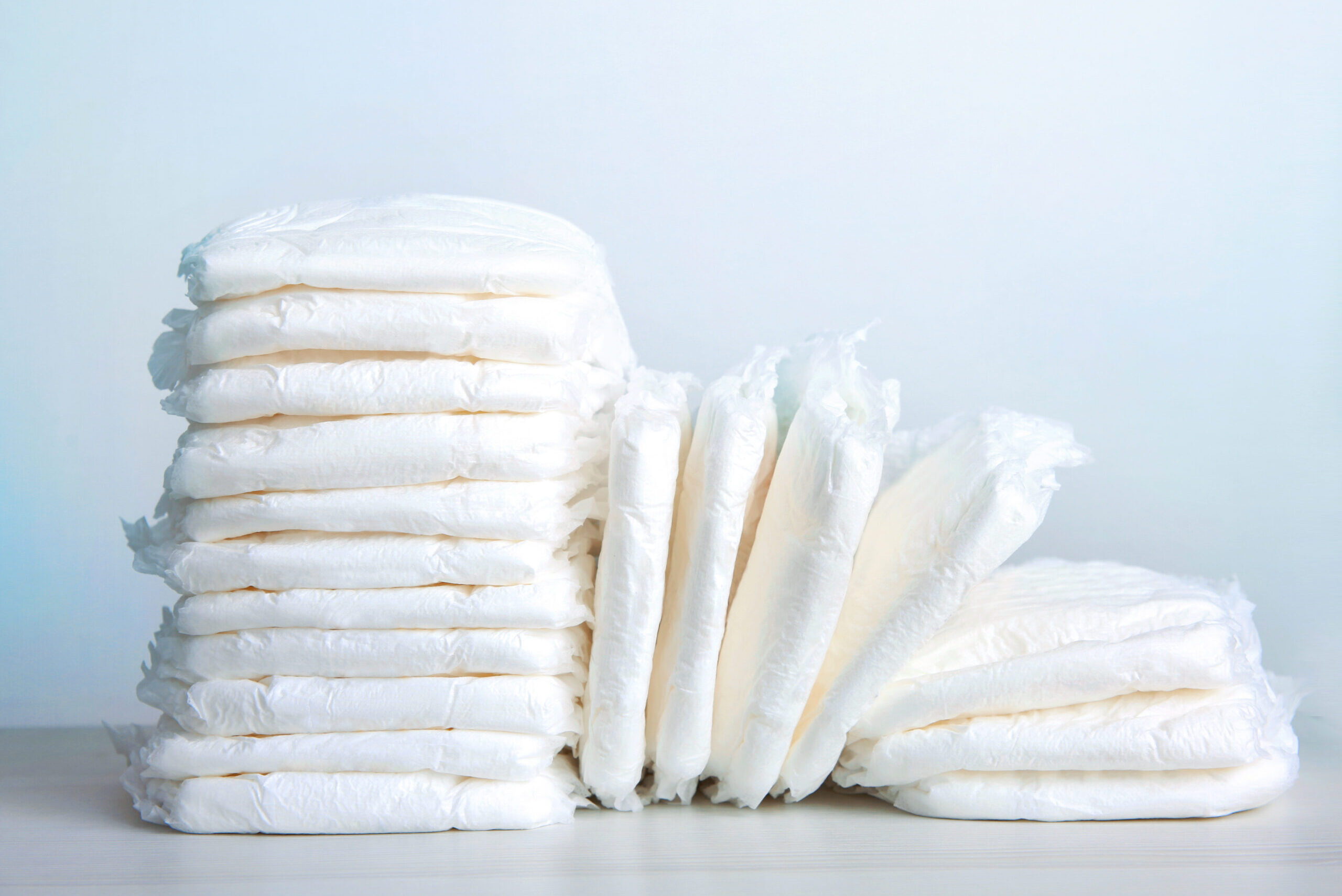 Stack of white baby diapers on table close up.